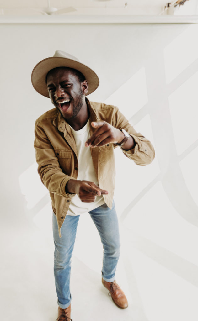 how to improve in authentic posing and get candid photos. black male smiling wearing a fedora